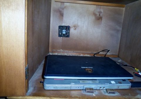 2000 Mercury Grand Marquis - A computer fan is mounted on the wall of a wooden cabinet containing two stacked laptops.