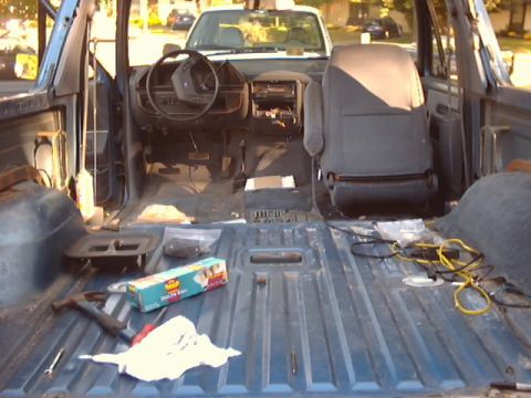 1990 Ford Bronco - Interior view of a 1990 Ford Bronco undergoing work, with parts removed and a second vehicle visible outside.