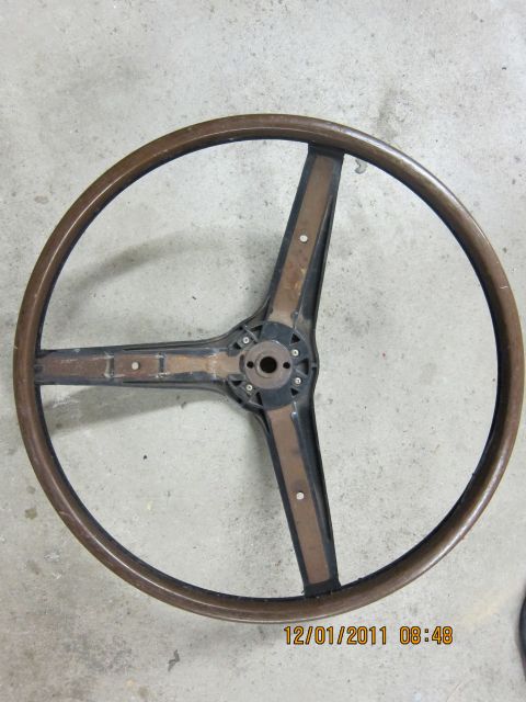 1969 Ford Mustang - A vintage wooden steering wheel is shown from above, resting on a textured gray floor.