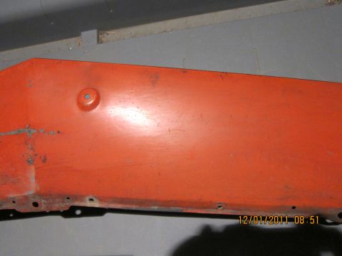 1969 Ford Mustang - Close-up of an orange painted metal part with visible mounting holes and a date stamp.