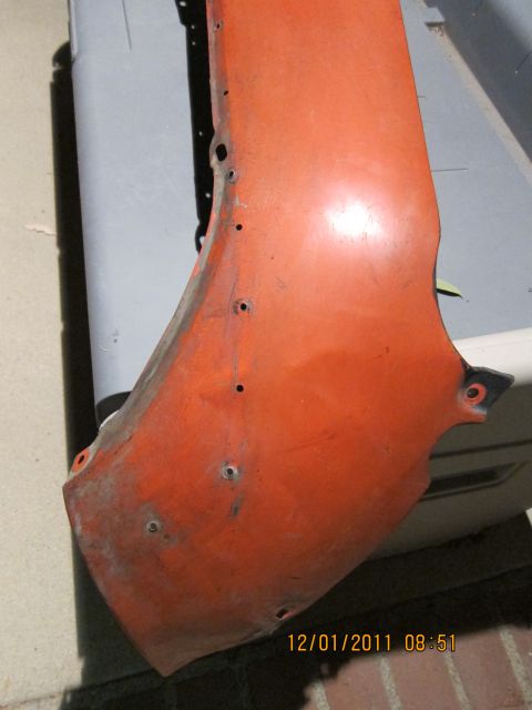 1969 Ford Mustang - A close-up view of an orange car fender shows multiple drilled holes for mounting hardware.