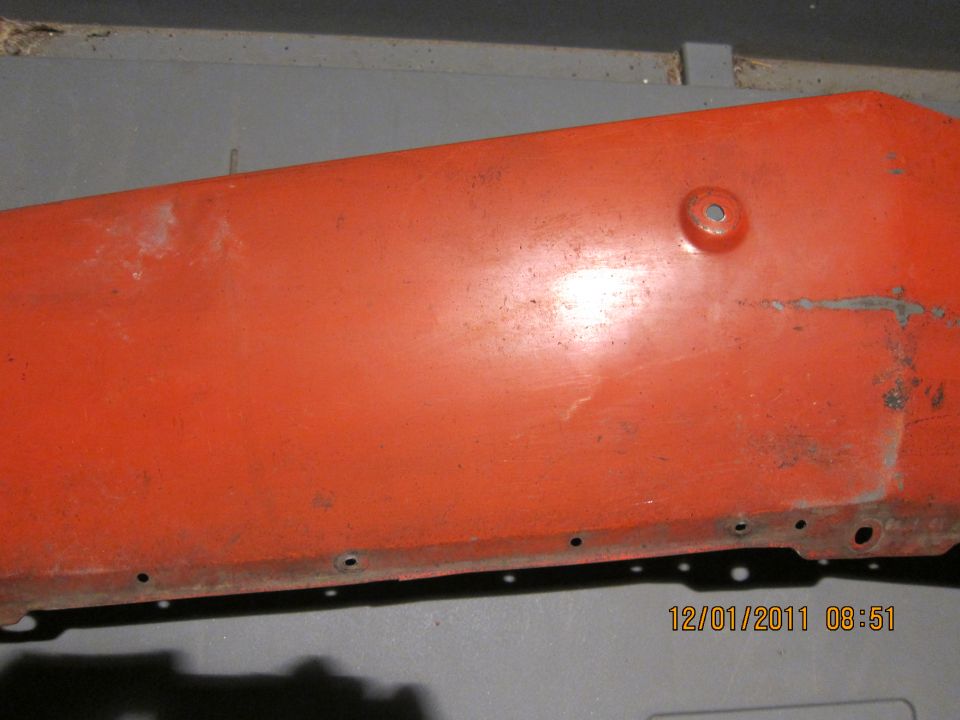 Orange car fender with rust and mounting holes