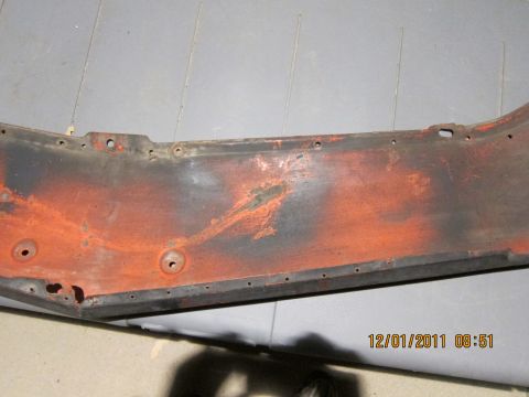 1969 Ford Mustang - This close-up shows a section of a weathered metal part with visible rust and orange paint.