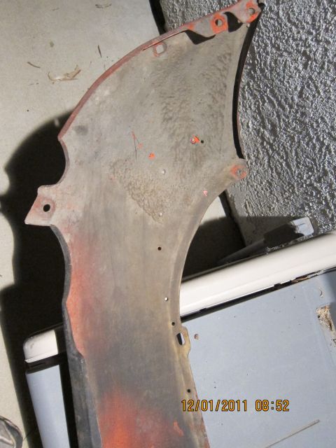 1969 Ford Mustang - This is a part of a vehicle fender, showing its interior side with mounting holes and remnants of orange undercoating.