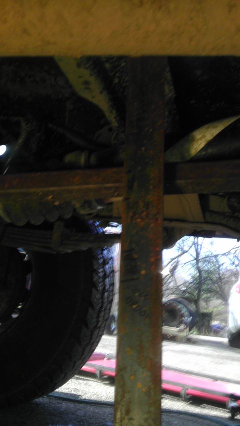 1989 Ford Bronco - A close-up view of a rusty suspension component and tire, likely from a vehicle's undercarriage.