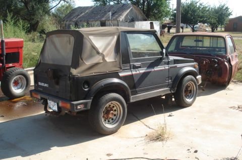 1986 Suzuki Samurai - A Suzuki Samurai and a rusty pickup truck cab are parked outdoors. A red tractor is also visible.