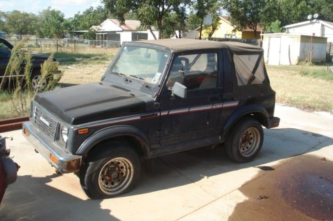 1986 Suzuki Samurai - This Suzuki Samurai is parked in a yard with a soft top and appears to have flat tires.
