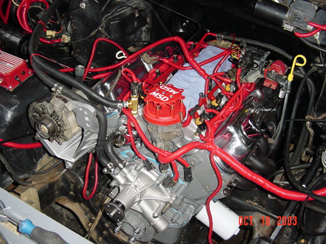 Engine bay with chrome valve covers, red MSD distributor and red plug wires, dated Oct 2003