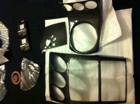 1990 Ford Probe - Several carbon fiber interior trim pieces are laid out, including pieces with circular and rectangular openings, along with packaging.