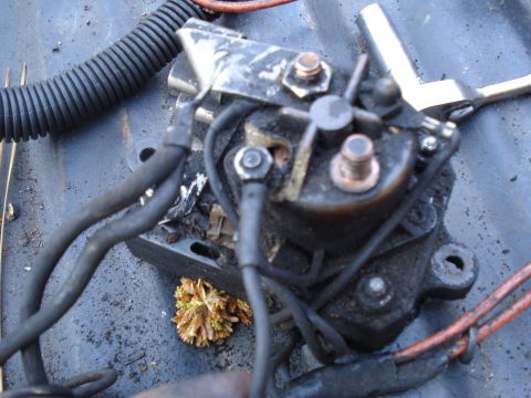 1989 Ford F-250 - Close-up of a starter solenoid with visible wear and tear, showing electrical connections and a small clump of debris.