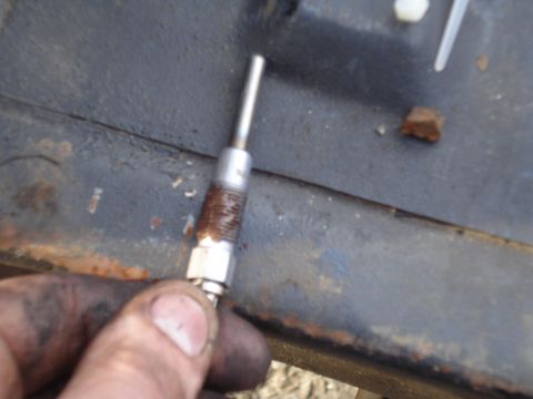 1989 Ford F-250 - A hand holds a glow plug, a component used in diesel engines to aid starting.