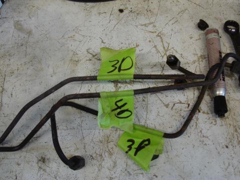 1989 Ford F-250 - Close-up of brake lines with handwritten labels on green tape, resting on a workbench surface.