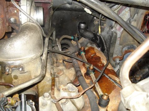1989 Ford F-250 - Close-up view of engine components including a turbocharger and exhaust manifold with visible rust and grime.