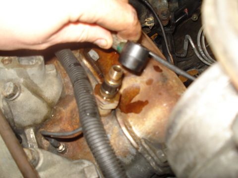 1989 Ford F-250 - Close-up of a hand working on an engine part, likely a sensor or fitting.