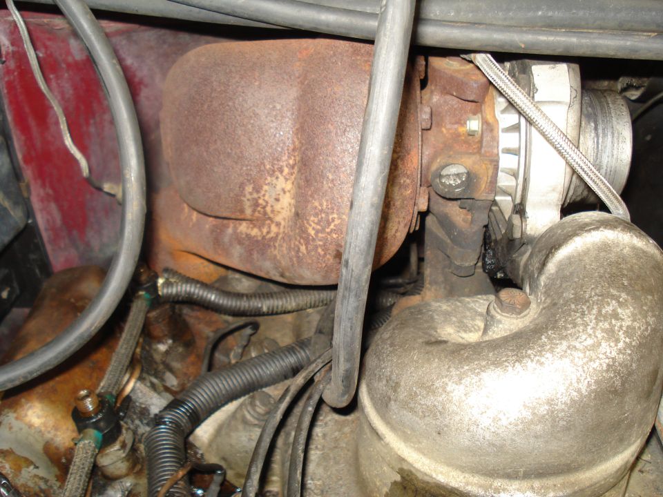 Close-up of a rusty turbocharger, alternator, and engine components