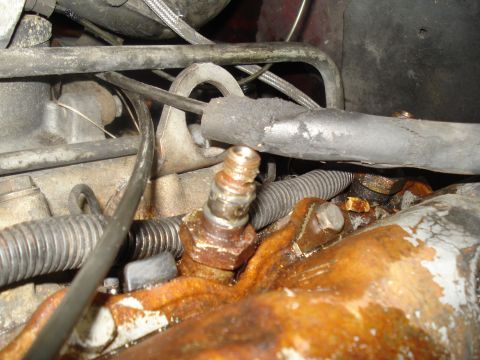 1989 Ford F-250 - Rusty engine part with attached hoses and metal lines, likely from an older vehicle.