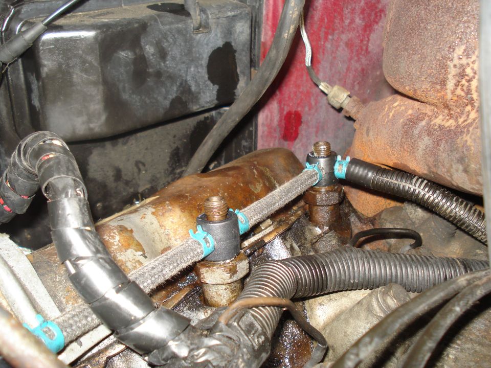 Engine bay with fuel lines and wiring harness. Red painted metal in background