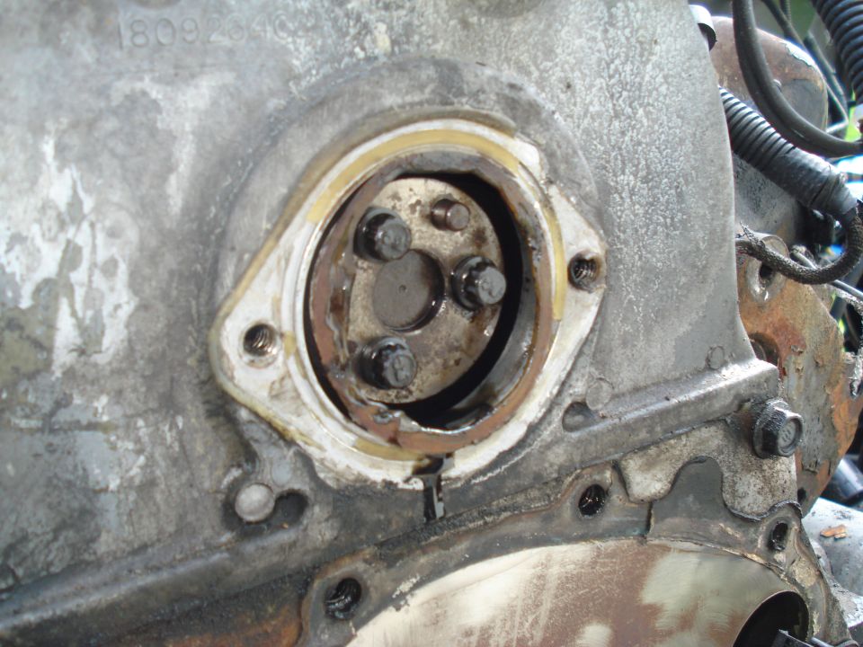 Close-up of engine timing cover seal area with bolts