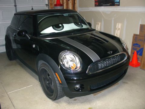 2010 MINI Cooper - A black MINI Cooper is parked in a garage, its windshield covered by a sunshade designed to look like cartoon eyes.