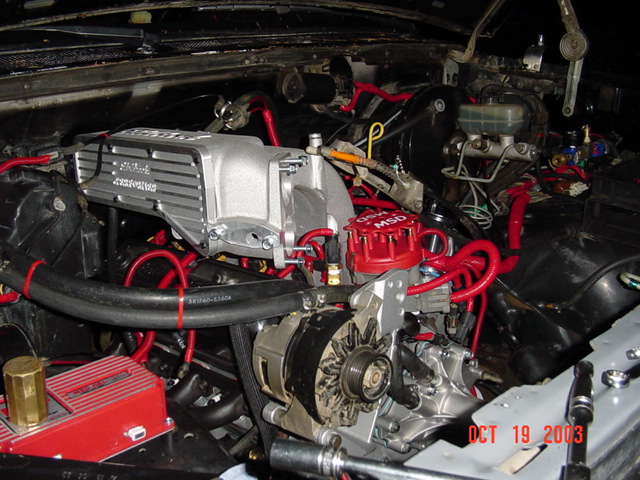 Supercharged V8 engine bay with chrome blower, red MSD cap and plug wires, dated Oct 2003