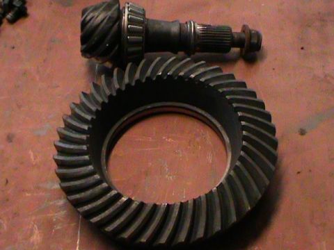 1995 Ford Bronco - A close-up view of automotive differential gears, a ring gear and a pinion gear, are shown on a surface.