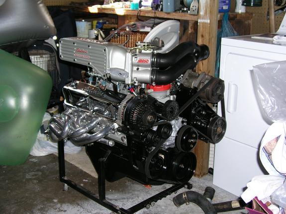 V8 engine with a silver supercharger on a stand, next to a washing machine