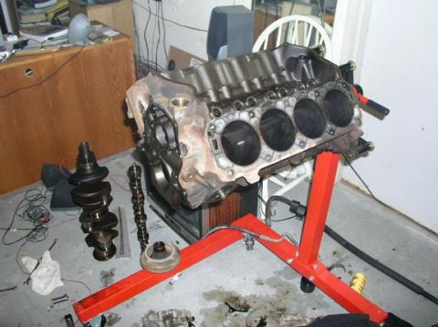 1996 Ford Bronco - Engine block and associated parts are laid out on the floor and an engine stand.