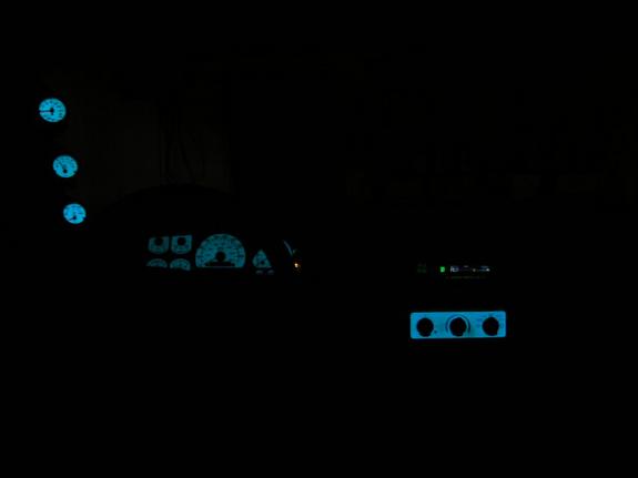 Car interior at night showing glowing blue gauges and climate controls