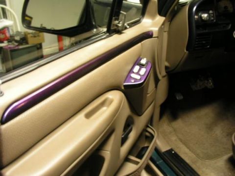 1996 Ford Bronco - The tan door panel features a metallic purple accent strip and power window controls.
