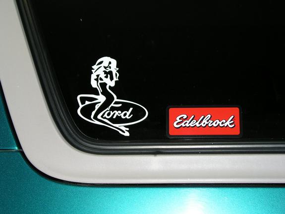 Car window with a white Ford logo sticker a pin-up girl and a red Edelbrock sticker