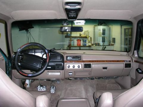 1996 Ford Bronco - The interior of a 1996 Ford Bronco features a tan dashboard with wood trim and a factory radio.
