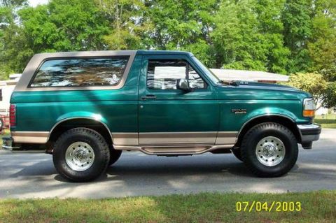 1996 Ford Bronco - Side view of a green 1996 Ford Bronco with a tan trim and removable top.