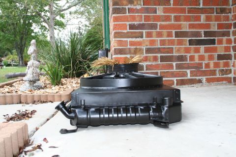 1996 Ford Bronco - A radiator and fan shroud assembly rests on a concrete surface outside a brick building.
