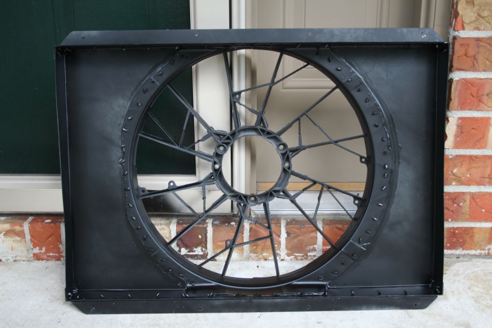 Black plastic radiator fan shroud with a circular opening and internal bracing