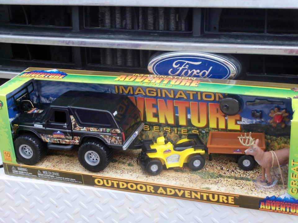 Toy Ford Bronco in box with trailer, ATV, and deer figure. Ford logo visible above