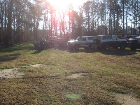 1994 Ford Bronco - Several SUVs are gathered in a wooded area on a sunny day.
