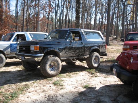 1994 Ford Bronco - This lifted black 1992 Ford Bronco is seen in a wooded area with other vehicles.