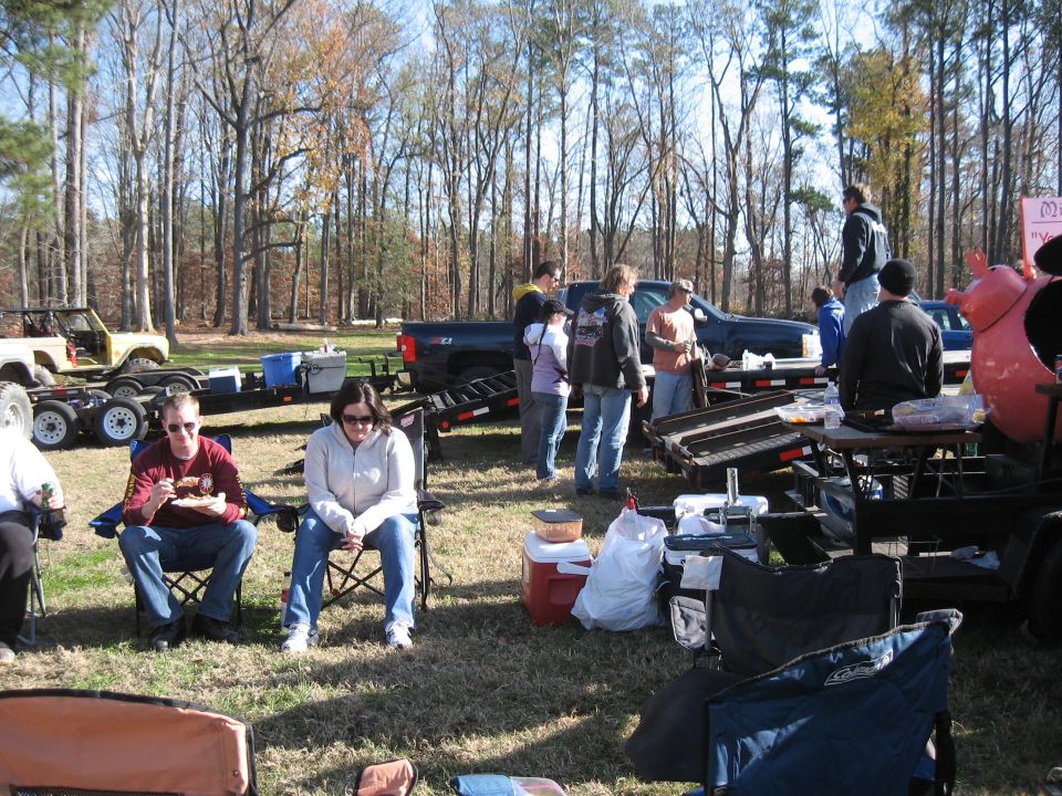 People sitting in chairs at an outdoor event with trucks and trailers