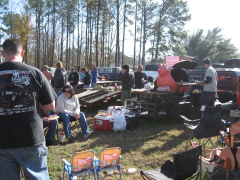 1994 Ford Bronco - An outdoor event with people gathered around grills and vehicles, with trees in the background.