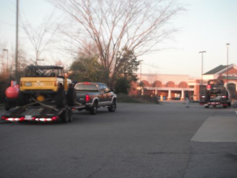 1989 Ford Bronco - A yellow 1989 Ford Bronco is transported on a trailer, towed by a pickup truck.