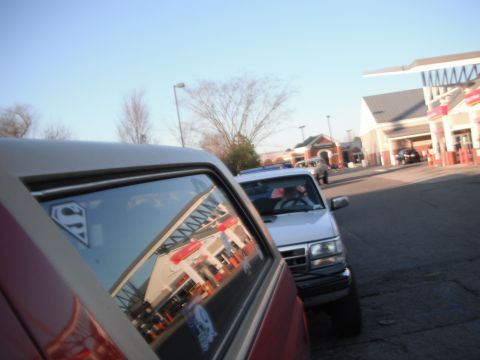 1989 Ford Bronco - A red SUV with a Superman logo on its window is parked next to a white SUV in a parking lot.