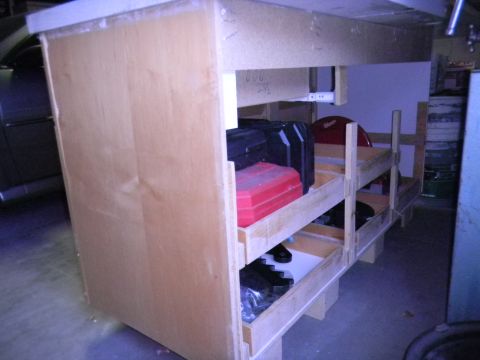 1997 Ford Ranger - A wooden workbench is filled with various toolboxes and storage containers.