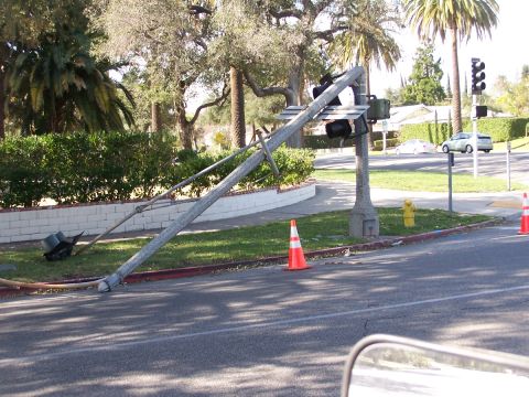 1990 Ford Bronco - A traffic light pole has fallen onto the grass next to the road, with two cars in the distance.