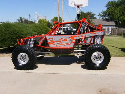 1986 Ford Bronco - Custom off-road buggy with flame graphics parked on a paved surface.