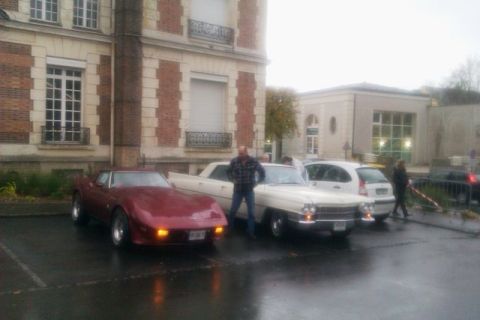 1991 Ford LTD Crown Victoria - Two cars, a red sports car and a white classic car, are parked outside a building.