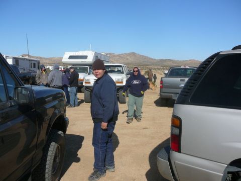 1988 Ford Bronco - Several vehicles and people are gathered in a dusty, outdoor location under a clear blue sky.