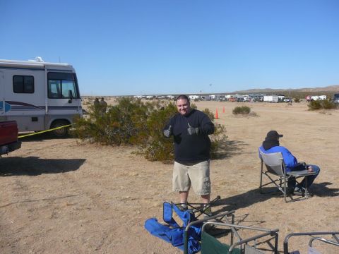 1988 Ford Bronco - A group gathers in a desert landscape with RVs and other vehicles present under a clear blue sky.