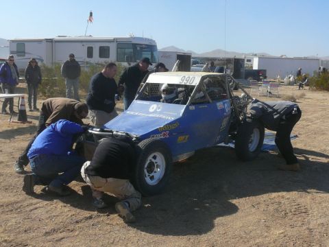 1988 Ford Bronco - A group of people are gathered around a blue off-road buggy, appearing to perform maintenance or repairs.