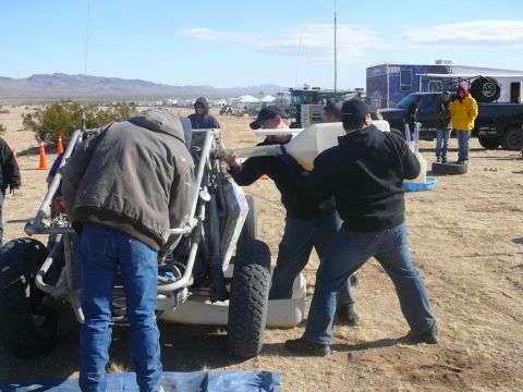 1988 Ford Bronco - Men refuel a custom off-road buggy in a desert environment with other vehicles present.