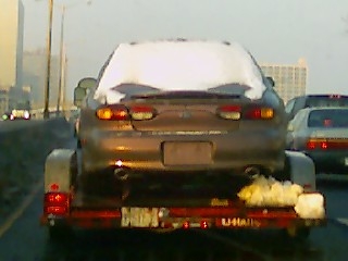 1997 Ford Taurus - Car transported on a trailer, with visible branding on the trailer itself.